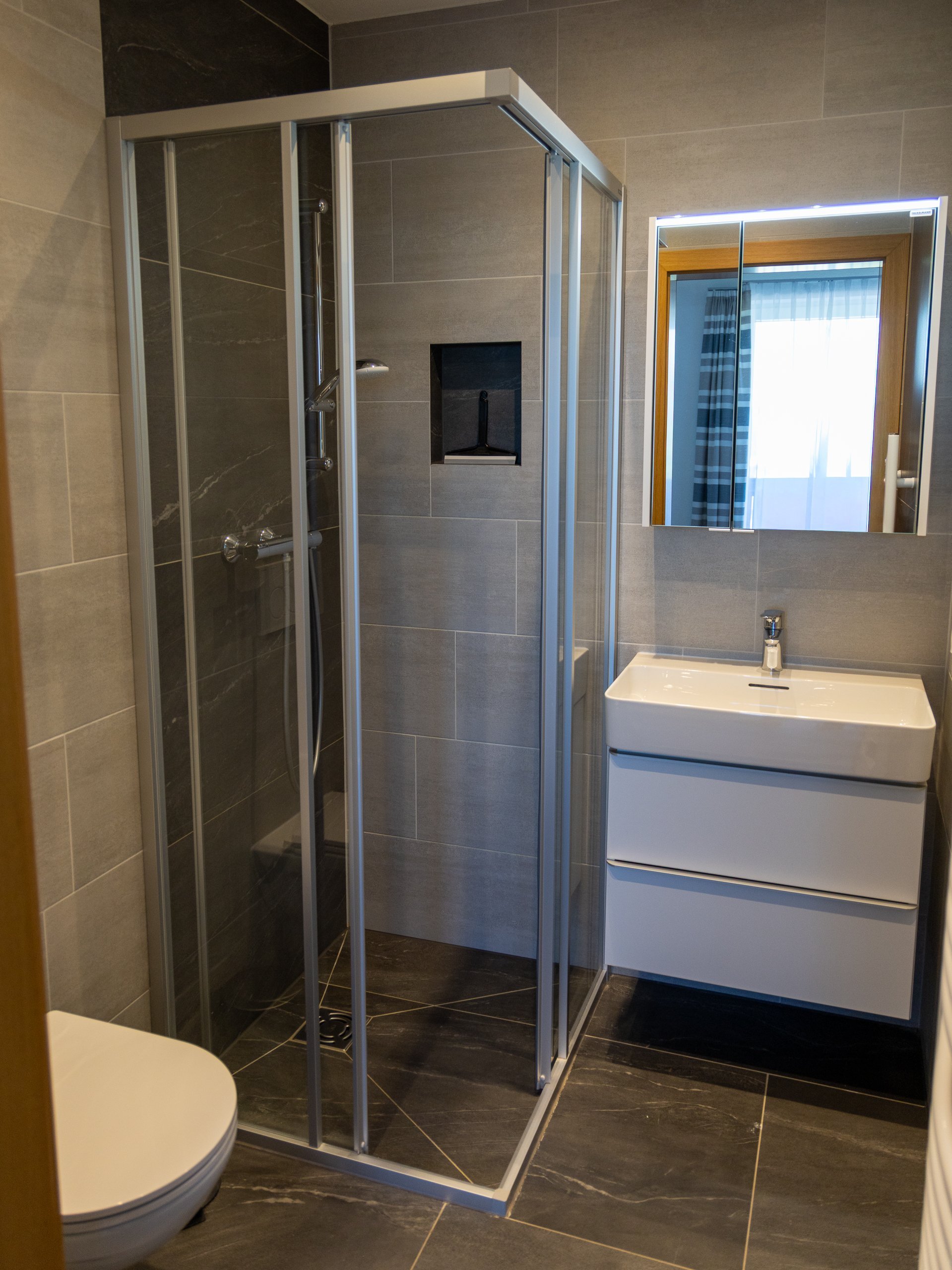 Modernes Badezimmer mit Duschbereich Zeitgemäßer Badezimmerbereich mit Glasdusche, Wandspiegel und eleganter Waschkommode