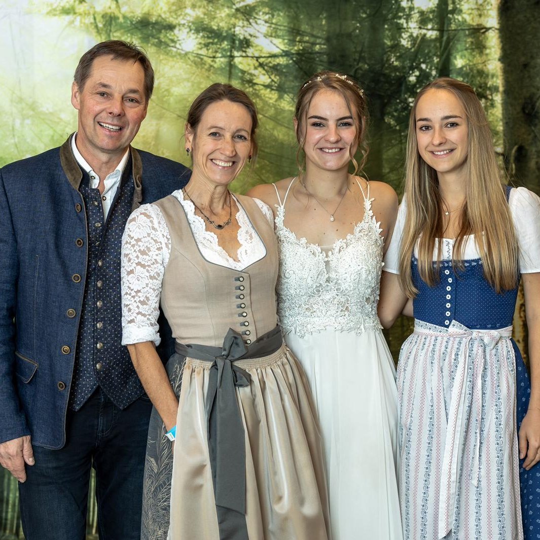 Familienfeier im traditionellen Hochzeitskleid Eine Familie posiert in traditioneller Tracht vor einem Waldhintergrund.